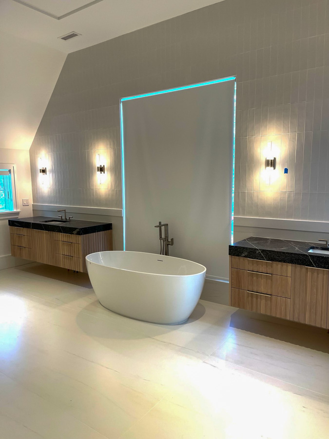 Porcelain tiled bathroom floor with freestanding bathtub in between two floating sink cabinets
